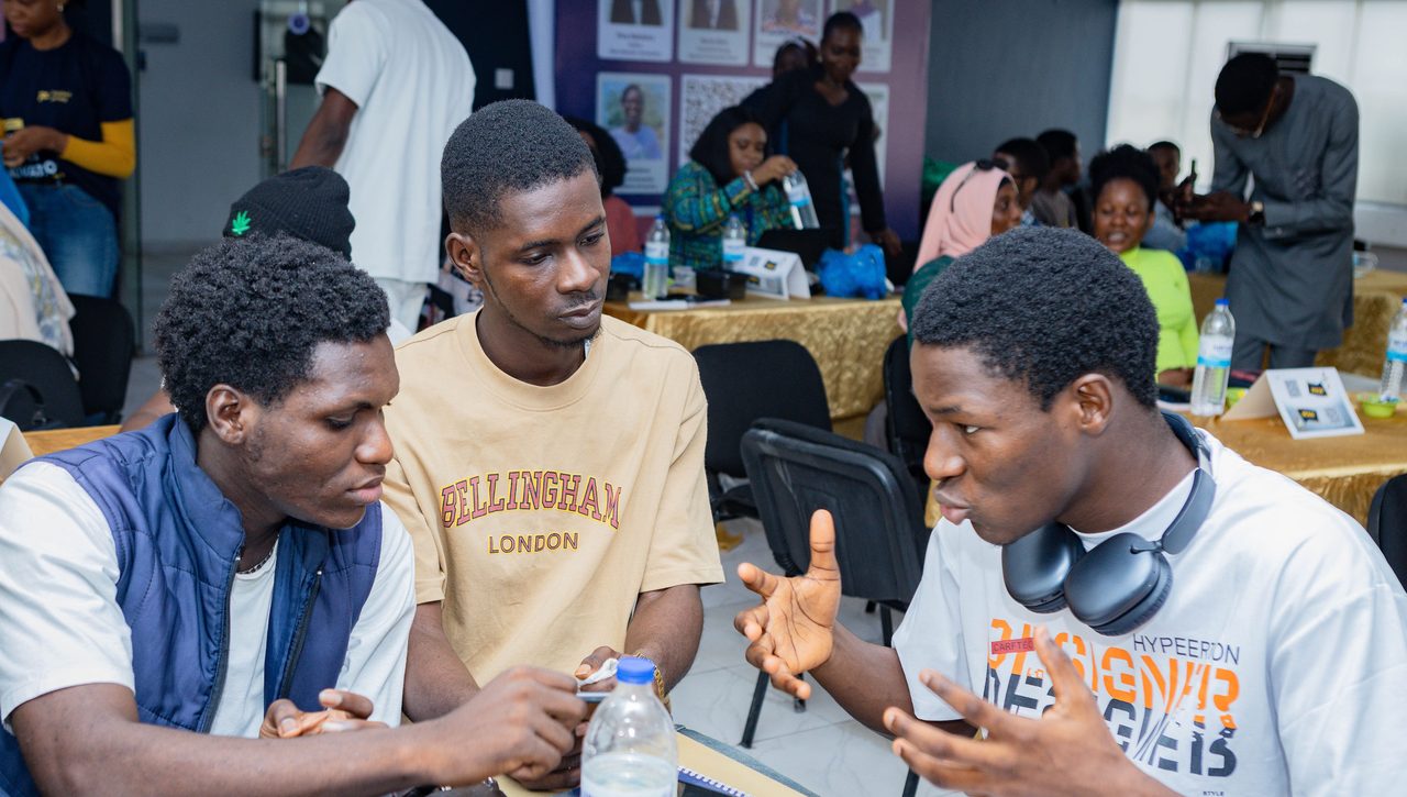 A Nigerian university student working on a laptop on campus